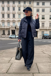 a lady in a dark blue down jacket, a black sweater and a pair of black pants